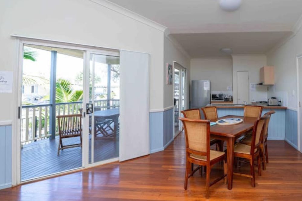 Dining table for six with sliding doors to the covered deck and kitchen beyond