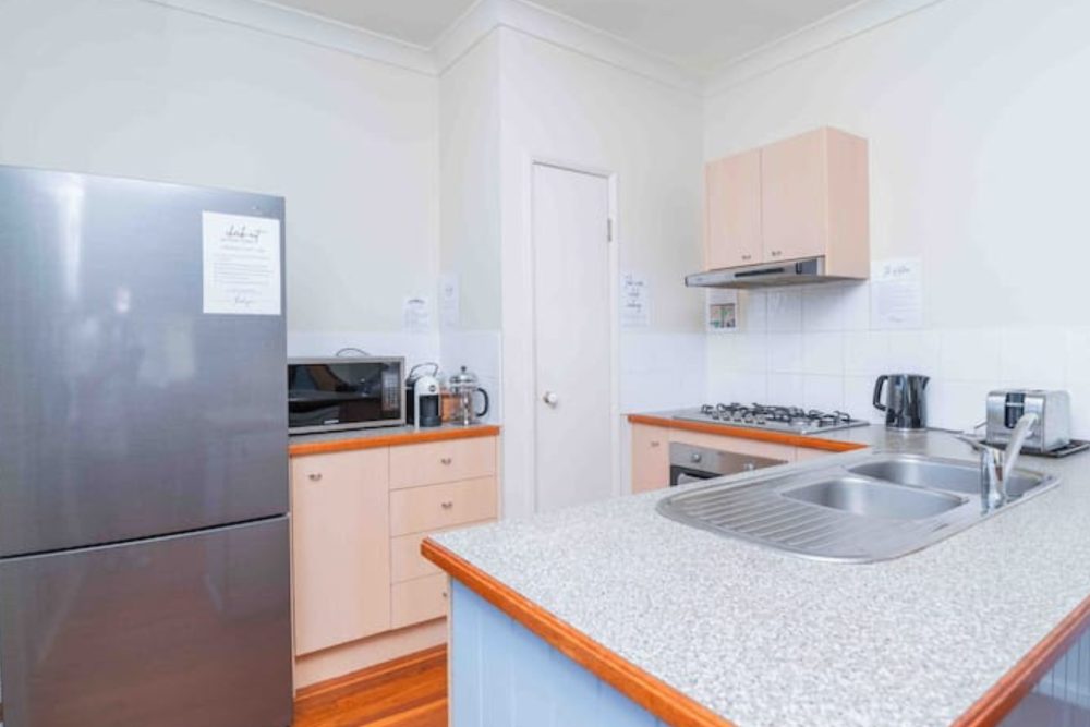 Self-Contained Kitchen with gas cooktop, oven, full-size fridge, microwave and breakfast bar