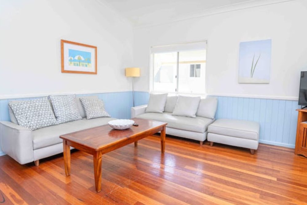 Living room with two sofas, polished timber floors and coastal artwork